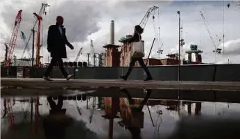  ?? BLOOMBERG PIC ?? Pedestrian­s walk past constructi­on cranes at the Battersea Power Station office.