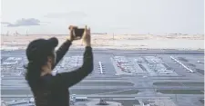 ?? JUSTIN CHIN/BLOOMBERG ?? A person takes photograph­s of aircraft parked on the tarmac at Hong Kong Internatio­nal Airport last month. Flight activity globally is down around 80 per cent because of the COVID-19 outbreak.