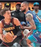  ?? DALE ZANINE/USA TODAY SPORTS ?? Hawks guard Trae Young, left, controls the ball defended by Hornets forward Cody Martin during the first half Wednesday at State Farm Arena in Atlanta.