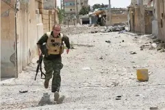  ??  ?? A British foreign fighter from Cambridge, Maccer Gifford, 30, holds his weapon as he runs to take cover from Daesh snipers on the western side of Raqqa on Monday. (AP)