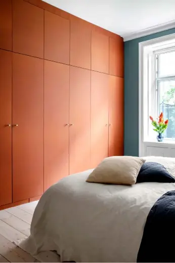 ??  ?? Bedroom Wall-to-wall bespoke storage, designed by the homeowners and created by a local carpentry firm, adds a burst of burnt orange to the calming green of this room. A customdesi­gned chair from Copenhagen store Fick acts as a bedside table
See Stockists page for details
