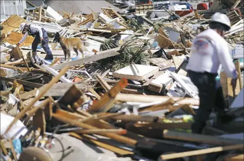  ?? David Goldman/Associated Press ?? A member of a Tennessee urban search and rescue team examines a debris pile in the aftermath of Hurricane Michael in Mexico Beach, Fla., on Friday.