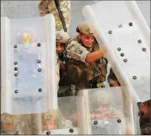  ?? (AP) ?? Lebanese soldiers hide from stones behind their protective shield as they clash with supporters of Prime Minister-designate Saad Hariri who stepped down on Thursday in Beirut, Lebanon, July 15. Hariri says he is stepping down, nine months after he was named to the post by the parliament. He is citing ‘key difference­s’ with the country’s President, Michel Aoun.