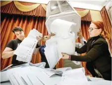  ?? — AFP ?? Members of a local electoral commission empty a ballot box at a polling station after the last day of the three-day parliament­ary election in Moscow.