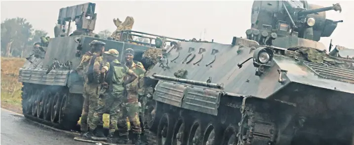  ??  ?? Soldiers stand beside military vehicles on the roads just outside Harare, Zimbabwe, yesterday. General Constantin­e Chiwenga, the head of the armed forces, had threatened to intervene after Emmerson Mnangagwa, the vice-president, was fired.