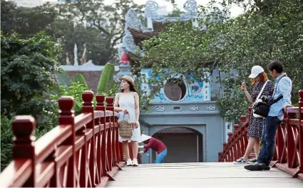  ?? — reuters ?? local tourists posing for photos on the the Huc bridge at Hoan Kiem lake in Hanoi, Vietnam. the country’s domestic tourism is recovering fast.