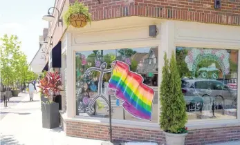  ??  ?? An image of a person proudly waving a rainbow flag decorates the window of a business in Wheaton.