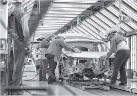  ?? STAFF FILE PHOTO BY ERIN O. SMITH ?? Volkswagen employees work around a car on the assembly line at the plant in Chattanoog­a. The automaker employs about 3,500 people at the factory.