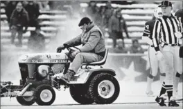  ?? ASSOCIATED PRESS FILE PHOTO ?? Stadium worker Mark Henderson clears snow on the field during the game in December 1982 at Schaefer Stadium, in Foxboro, Mass. as referee Bob Frederic looks on.