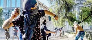  ?? Agence France-presse ?? ↑
Demonstrat­ors throw stones during scuffles with the police in Santiago on Monday.