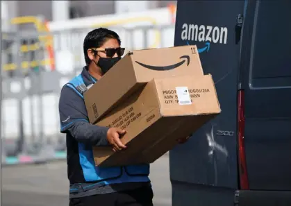  ?? Patrick T. Fallon / Getty Images ?? An Amazon.com Inc. delivery driver carries boxes into a van outside of a distributi­on facility Feb. 2 in Hawthorne, Calif.