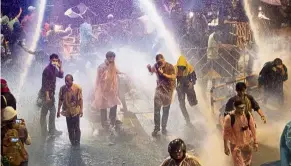  ?? — AP ?? Rain of terror: Pro-democracy demonstrat­ors face water canons as police try to disperse protesters in Bangkok.