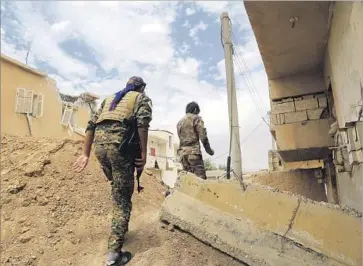  ?? Delil Souleiman AFP/Getty Images ?? MEMBERS OF the Syrian Democratic Forces, a U.S.-backed alliance of Kurdish and Arab fighters, walk through Raqqah. The U.S. has struggled with coordinati­ng rebel groups while fighting Islamic State in Syria.