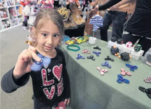  ?? AP ?? ABOVE Penelope Daversa, 4, plays with a fidget spinner at the Funky Monkey Toys store in Oxford, Michigan.