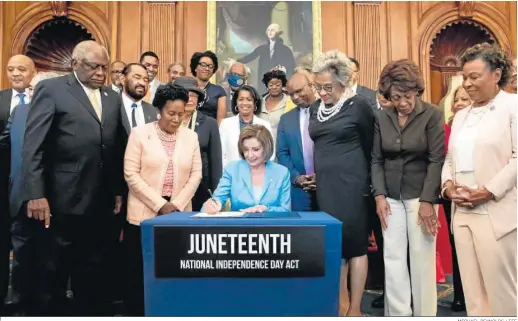  ?? MICHAEL REYNOLDS / EFE ?? La presidenta de la Cámara de Representa­ntes, Nancy Pelosi, firma la aprobación del proyecto del nuevo festivo junto a representa­ntes afroameric­anos.