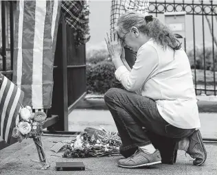  ?? Yi-Chin Lee / Staff photograph­er ?? Suzette Renee Drab prays after leaving flowers at the gate outside of former President George H.W. Bush’s home. Houstonian­s found their own ways to say farewell to the former president.