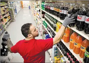  ?? AP/MATT ROURKE ?? Albert Delarosa stocks shelves with Coca-Cola products Thursday at the IGA supermarke­t in the Port Richmond neighborho­od of Philadelph­ia. IGA has hung signs in its stores denoting products affected by the soda tax.