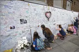  ?? TIM IRELAND / ASSOCIATED PRESS ?? People write on a wall put up as a tribute to Grenfell Tower residents Thursday at a community center in London. The death toll from the early-Wednesday fire rose to 17 and is certain to climb further, authoritie­s warned.