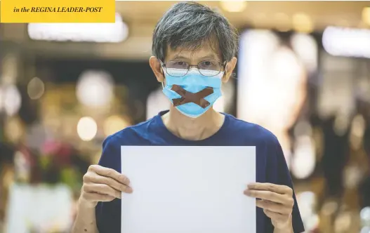  ?? PAUL YEUNG / BLOOMBERG ?? A demonstrat­or in a protective mask holds a blank sign at a protest at a Hong Kong shopping mall Monday, after a key slogan often used by protesters was declared illegal.