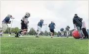  ?? GARY YOKOYAMA THE HAMILTON SPECTATOR ?? St. Mary Catholic Secondary School’s junior football squad run laps along the sidelines of their new artificial turf field.