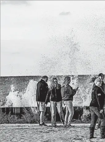  ??  ?? Visitors stand near crashing Lake Michigan waves at the Big Sable Point Lighthouse at Ludington State Park in Ludington, Michigan, on Sept. 30. A new seawall was put in place to protect the historic lighthouse.