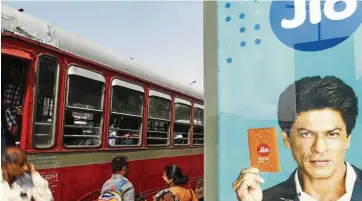  ?? Bloomberg ?? Fee boost: An advertisem­ent featuring Bollywood actor Shah Rukh Khan for Reliance Jio, the mobile network of Reliance Industries Ltd, is displayed at a bus stop in Mumbai. The licence fee reduction can help Reliance Jio accelerate its broadband services offering. —