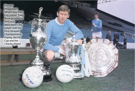  ??  ?? Former Peasedown Miners and Bath City player Tony Book pictured in 1970 as a Mancheter City player with the First Division Championsh­ip trophy, the FA Cup and the Charity Shield