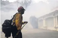  ?? AP PHOTOS ?? A firefighte­r walks in front of a house as smoke from an advancing wildfire fills the air last Friday.