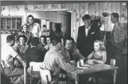  ?? Courtesy Photo/Shiloh Museum of Ozark History ?? Actors and extras at the Hitchin Post Cafe in Springdale in September 1951 with actor John Fontaine (seated at front table, middle) and locals Betty Walker and Teena Carpenter (seated at back table, left and right, respective­ly) and Wayne High (standing at back table).Wonder Valley was the first motion picture shot entirely in Arkansas.