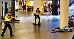  ?? ASSOCIATED PRESS PHOTO ?? Dutch police point their guns at a wounded 19-year-old man who was shot by officers after he allegedly stabbed two Americans in the central railway station in Amsterdam.