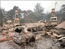  ?? RICH PEDRONCELL­I/AP PHOTO ?? The burned remains of a car sit in the driveway of a home near the Silverado Country Club and Resort on Tuesday in Napa, Calif.