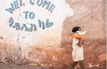  ??  ?? An Eritrean refugee child walks in front of a sign at Mai Aini Refugee camp, in Ethiopia.