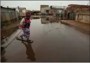  ?? (AP/Themba Hadebe) ?? A woman crosses a waterlogge­d street Thursday after rainfall in Thokoza, east of Johannesbu­rg, South Africa.