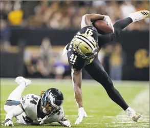  ?? Jonathan Bachman / Getty Images ?? The Saints’ Alvin Kamara is tripped up by the Eagles’ Cre'von LeBlanc during Sunday’s NFC playoff game in New Orleans.