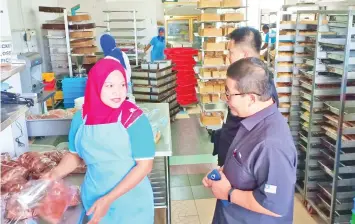  ??  ?? Kamal (right) asking an employee at a bakery shop in Tawau about her salary yesterday.