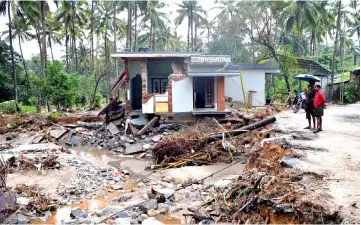  ??  ?? Indian people look at a house destroyed by a landslide at Kannapanak­undu village, about 422 km north of Trivandrum, in Kerala. — AFP photo