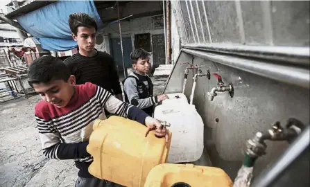  ??  ?? Water woes: Youths filling bottles and jerricans with drinking water from public taps at the Rafah refugee camp in the southern Gaza Strip. — AFP