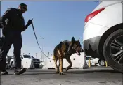  ?? MARIO TAMA / GETTY IMAGES ?? A Customs and Border Protection officer with a canine inspects vehicles entering the country at the San Ysidro Port of Entry in California on Monday. Arizona and Texas are sending National Guard troops to the southern border in response to a decree by...