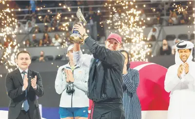  ?? — Gambar AFP ?? KEJUARAAN KETIGA: Swiatek menjulang trofi kemenangan selepas menundukka­n Rybakina pada final tenis wanita Kejohanan Terbuka Qatar di Doha.