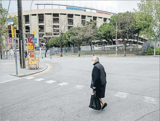  ?? MANÉ ESPINOSA ?? Una mujer protegida por una mascarilla cruzando ayer la calle con el Camp Nou al fondo