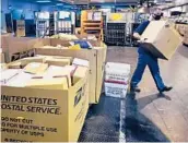  ?? ?? A worker carries a large parcel at the U.S. Postal Service sorting and processing facility Nov. 18 in Boston. Shippers are gearing up for another holiday crush.