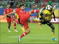  ?? AP PHOTO/MATT YORK ?? Canada's Michael Petrasso moves to strike the ball as Jamaica's Kemar Lawrence heads it out of the way during a CONCACAF Gold Cup quarterfin­al soccer match, Thursday in Glendale, Ariz. Jamaica won the match 2-1 and advances to the semifinal.