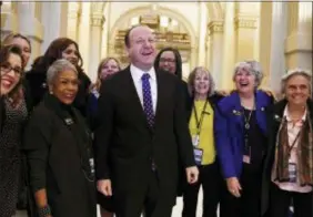  ?? AARON ONTIVEROZ/THE DENVER POST VIA AP, FILE ?? Colorado Governor-Elect Jared Polis, center, jokes with members of the state house and senate before his inaugurati­on at the Colorado State Capitol in Denver. Health care proposals are among the first actions for some new Democratic governors and Democratic­ally controlled legislatur­es. Expanding access to care was a rallying point for the party in the 2018 elections.