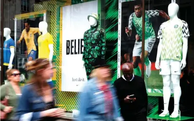  ?? Frank Augstein/Associated Press ?? ■ People walk by Nigerian and Brazilian national soccer team jerseys on June 5 that are on display at a shop in London. With just days to go before the FIFA World Cup, some winners and losers have emerged among the often wild and wacky team jerseys.