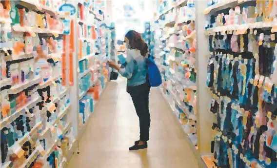  ?? ADIL BOUKIND LE DEVOIR / MONTAGE LE DEVOIR ?? Pharmacie Jean Coutu. À la pharmacie, la clientèle est éparse en ce début d’après-midi. À deux pas de l’entrée, une employée masquée accueille tous les clients d’un généreux nuage alcoolisé sur les mains. Au comptoir des prescripti­ons, pharmacien­s et employés sont tous masqués. Et les clients ? « La plupart des clients portent un masque, car vous savez, on a beaucoup de personnes âgées », insiste une employée. À la caisse, une affiche jaune fluo apposée sur la paroi de plexiglas rappelle la consigne « d’un mètre » à respecter entre clients et employés.