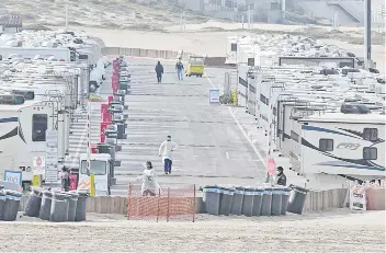  ?? — AFP photo ?? Medical staff walk among RV campers in a beachside parking lot being used as an isolation zone for people with Covid19 at Dockweiler State Beach in Los Angeles, California.