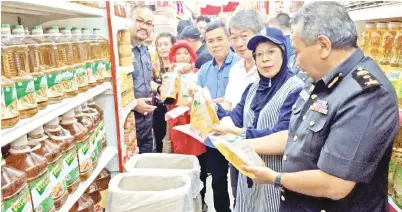  ??  ?? YAHYA (kanan) memberi makluman kepada Jainab (dua kanan) tentang minyak paket yang termasuk dalam barangan kawalan KPDNKK. Turut kelihatan Penolong Pengurus Pasaraya CKS Donggongon Henry Chong (tiga kanan).