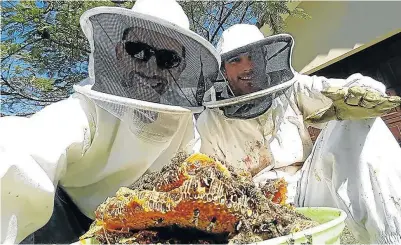  ?? Picture: MARK ANDREWS ?? DRIPPING GOOD: Part-time beekeeper Chad Symons, right, shows how a hive removal is done. In this instance, more than 24kg of raw honey was extracted from the ceiling of a home in Gonubie.