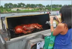  ?? NICHOLAS BUONANNO — NBUONANNO@TROYRECORD.COM ?? A person takes a photo of a pig roast made by B-Rads during Troy Pig Out on Saturday.