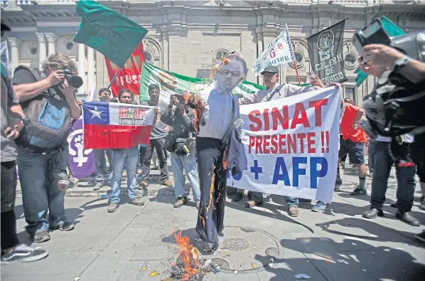  ??  ?? UNDER FIRE: Demonstrat­ors burn an effigy of the late Chilean dictator General Augusto Pinochet during a protest demanding a comprehens­ive reform of the country’s privatised pension system, which remains from his regime.